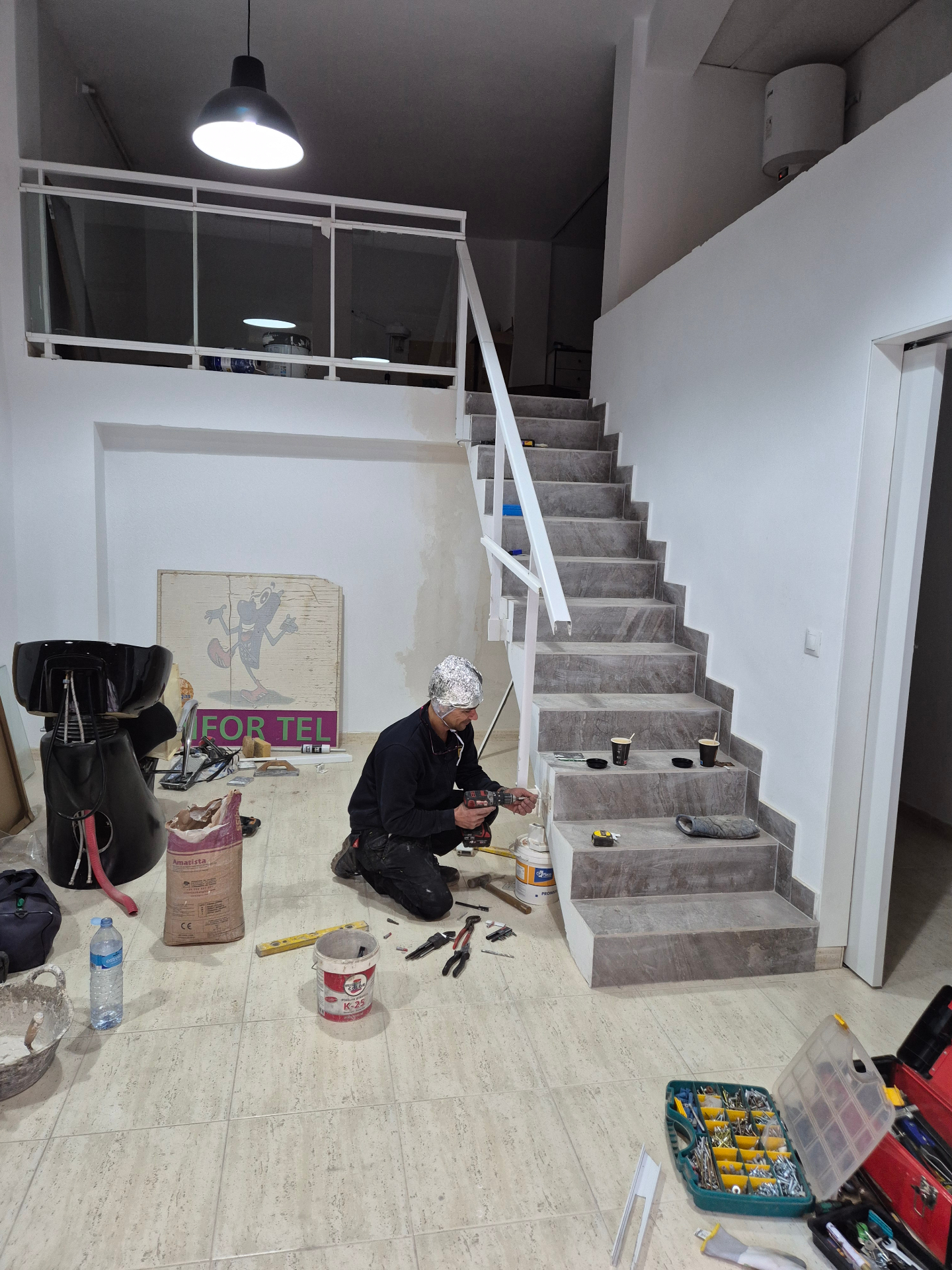 En Roger instal·lant una barana metàl·lica en una escala interior